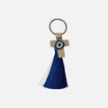 Mati Made beige faux-leather cross keychain with an evil eye charm and a vibrant blue silk-style tassel.