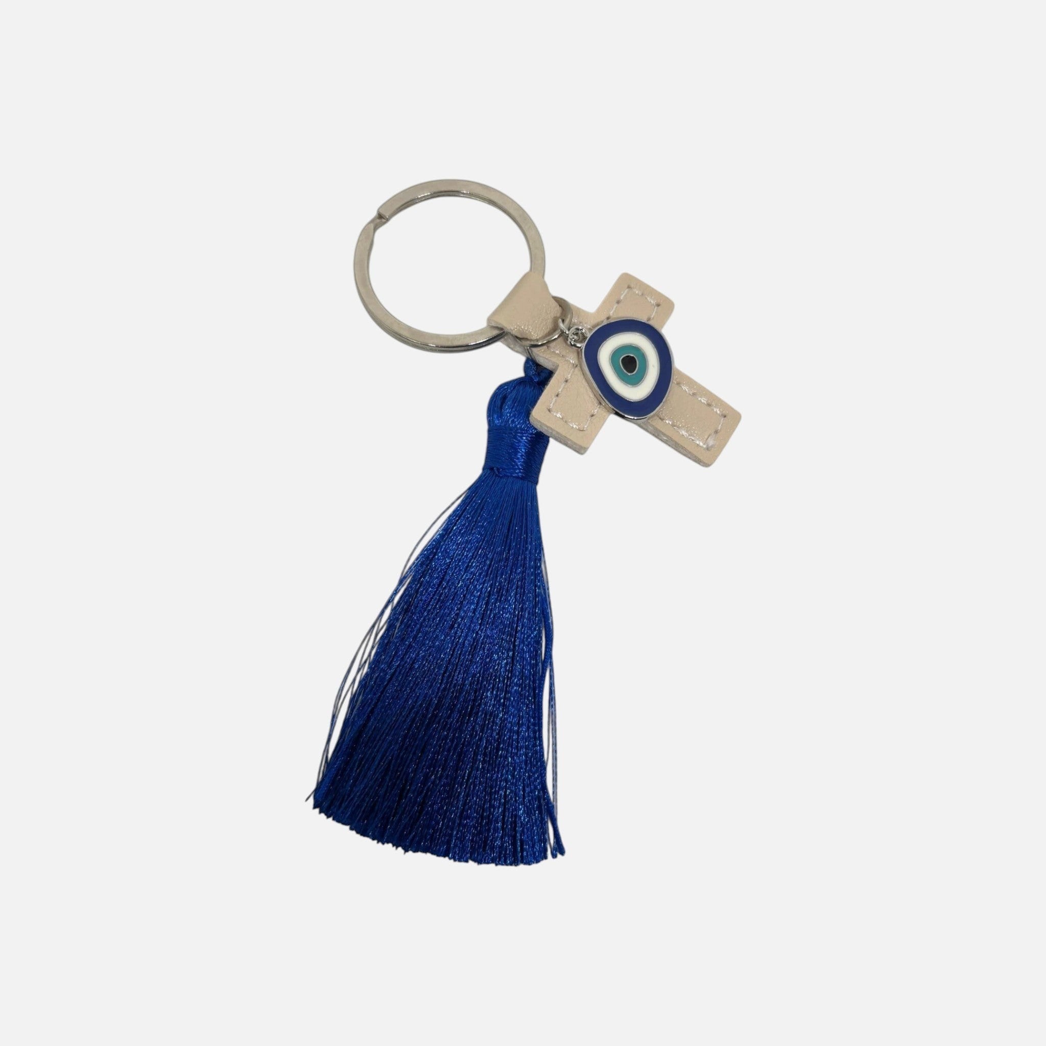 Mati Made beige faux-leather cross keychain with a blue evil eye charm and a vibrant blue silk-style tassel.