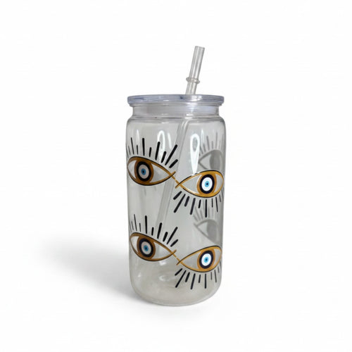 Mati Made clear glass can tumbler featuring a gold and blue evil eye motif, complete with a lid and reusable straw.