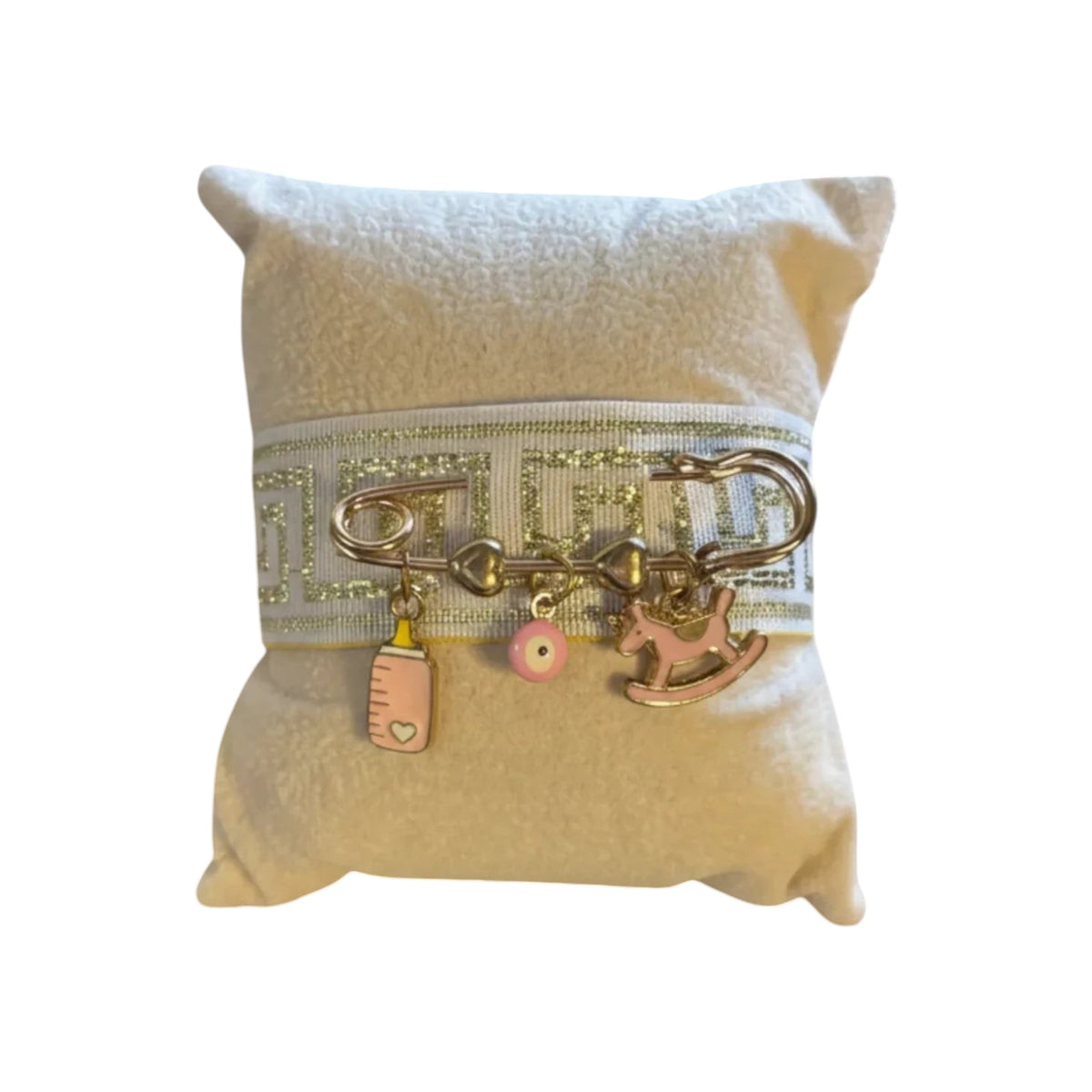 Mati Made handcrafted Filaxto pillow in neutral fabric with a silver ribbon and baby bottle, mati, and rocking horse charms.