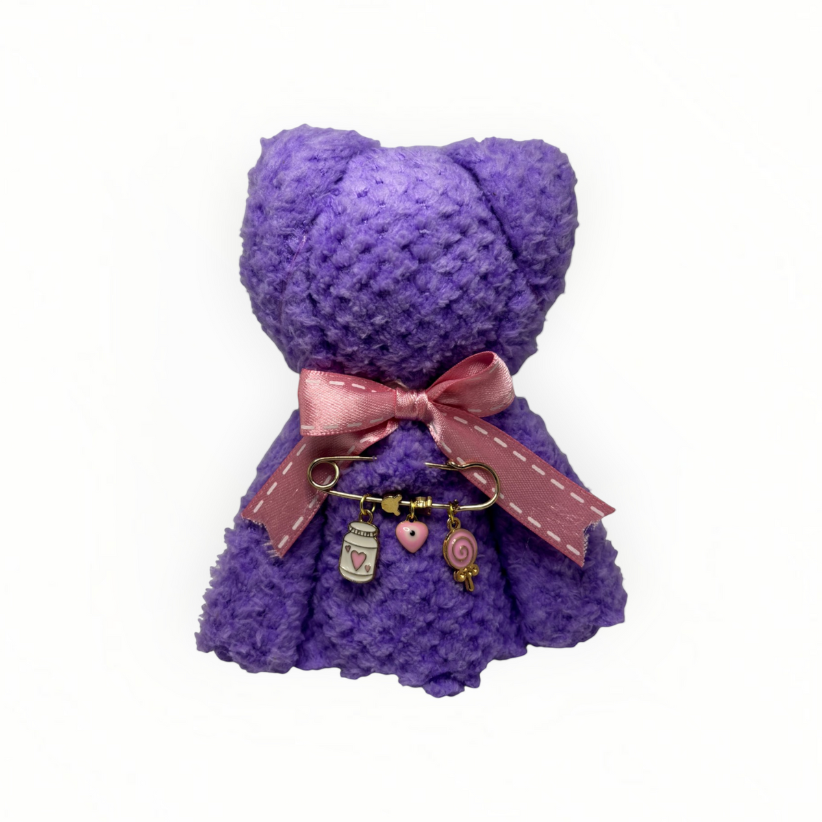 Mati Made purple teddy cloth face washer with pink ribbon and gold charm pin featuring a bottle, heart, and lollipop.