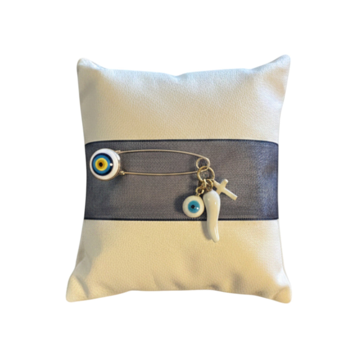 Mati Made white faux leather Filaxto pillow with blue ribbon, gold charm, evil eye bead, cross, and white chilli.