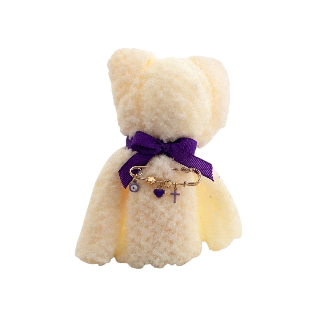 Mati Made white teddy cloth face washer with a purple ribbon and gold filaxto charm featuring a heart, cross, and mati.